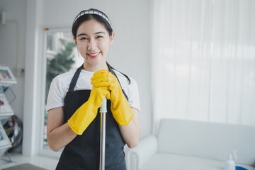 Asian women wear uniforms to prepare for housekeeping work, Wear an apron and rubber gloves to protect against cleaning chemicals, housekeeper is smiling happily before starting work, cleaning idea..