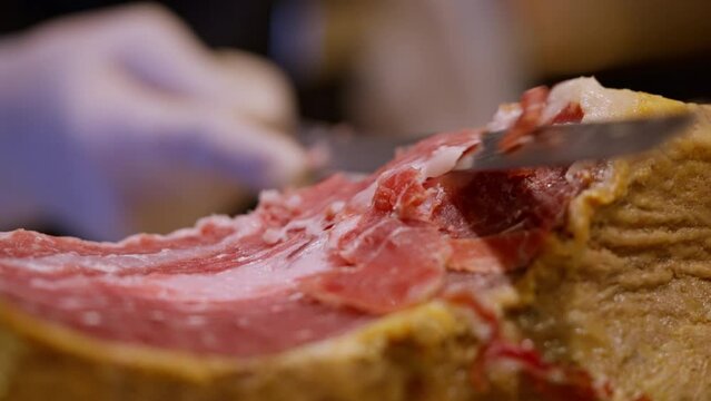 Skilled chef carving Iberico ham a culinary slices the exquisite Iberian delicacy. The precision and artistry of the process capture the essence of gourmet expertise. High quality 4k footage