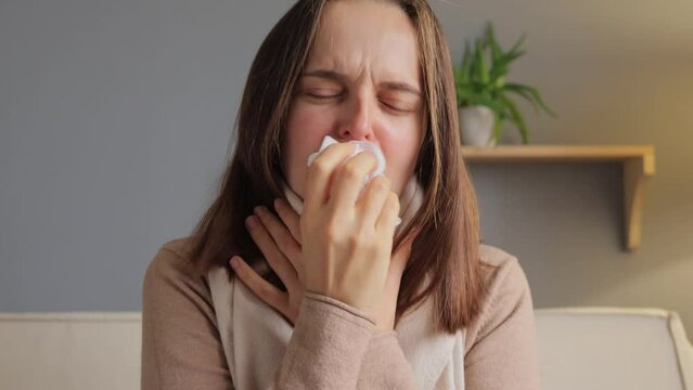 Disease infection. Unhealthy medicine. Healthcare illness. Catch flu. Sick woman. Covid infection. Exhausted woman sitting on sofa suffering flu symptoms coughing room interior.