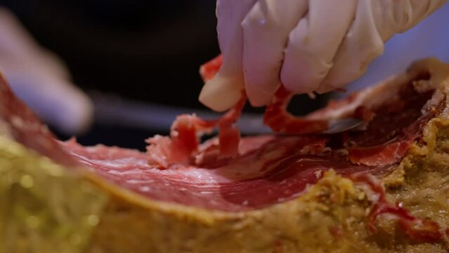 slicing Iberico ham an artisan at work, meticulously carving thin slices of the coveted Iberico ham. The rich marbling and savory aroma promise a culinary. High quality 4k footage