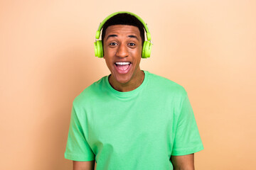 Photo portrait of handsome young male excited headphones listen music wear trendy green outfit isolated on beige color background