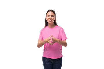 young slim european woman with black straight hair is dressed in a pink t-shirt on a studio background with copy space