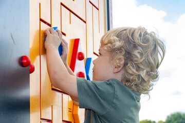 Little boy explores outdoor rebus on playground - obrazy, fototapety, plakaty