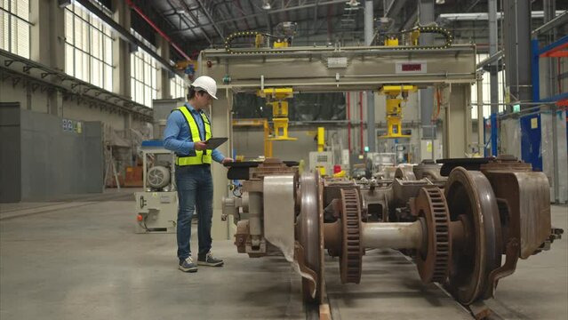 Electric train engineer inspect electric train machinery with tablets according to inspection round after the electric train is parked in the electric train's repair shop