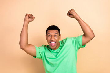 Fototapeta premium Photo portrait of handsome young male raise fists celebrate victory scream wear trendy green outfit isolated on beige color background