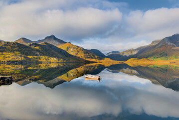 wonderful mountainous landscape in Norway reflected on the water surface with a small rowboat