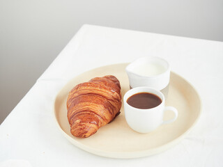 continental breakfast on the table croissant, coffee cup and milk jug