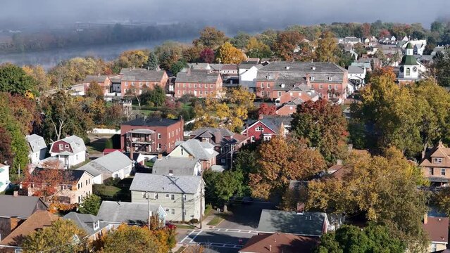 A slow forward aerial establishing shot of a small town's residential district in early Autumn. Foggy Ohio River in the distance. Pittsburgh suburbs.  	