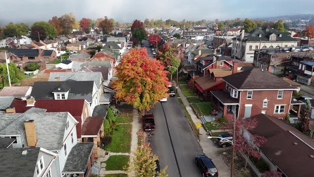 A low forward aerial view of the residential district of a small New England town on a foggy early autumn morning.  	