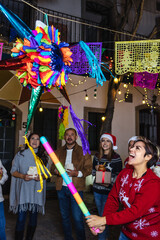 Hispanic family breaking a pinata at traditional mexican posada celebration for Christmas in Mexico...