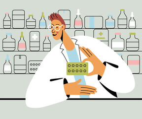 Pharmacist man holding medicine pills at the counter in a pharmacy opposite of shelves with medicines.