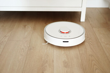 Wireless autonomous robotic vacuum cleaner vacuums with brushes under commode at living room....