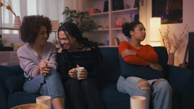 Offended African American woman looking at two best friends ignoring her, fight