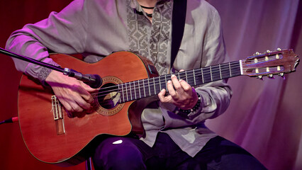 man playing an acoustic guitar in front of a microphone