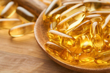 Close up capsules with Vitamin D, E or Omega 3,6,9 fatty acids in bottle on old wooden backgrounds. Food supplement oil filled fish oil. Natural supplements for healthy good life concept. Banner.