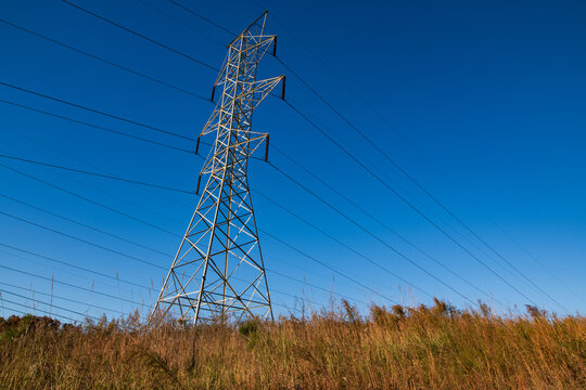 Powerlines and a transmission tower against a clear blue sky