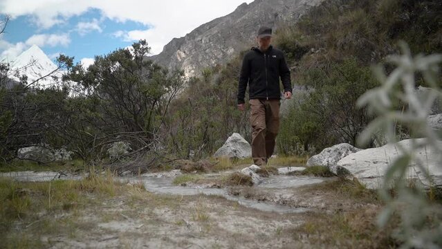 young caucasian man hiking through the mountainous landscape of the cordillera blanca in the Andes mountains of Peru near laguna Paron.