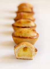 Pasticciotto leccese pastries filled with egg custard cream on a white table in a line, close up