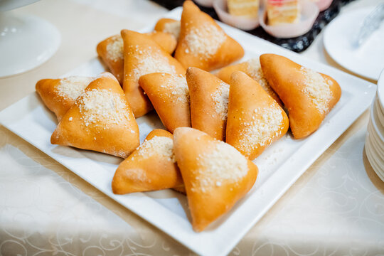 Baked cabbage pies, breakfast pastries, pies lying in a heap on a plate, sweet apple pies, catering.