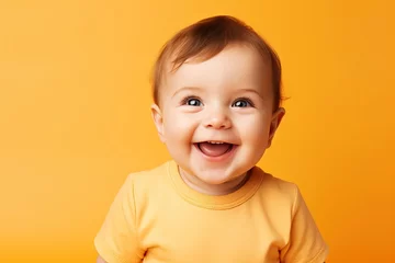 Fototapeten baby smiling and looking up to camera on a yellow background © Kowit