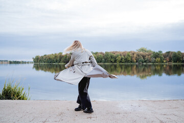 Autumn walk in the park on the shore of the lake, a girl dancing on the street by the water, a gray...