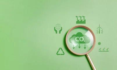 Deurstickers Magnifying glass with reduce CO2 emissions carbon symbol on green background for climate change to limit global warming and sustainable development and green business concept © Pakin
