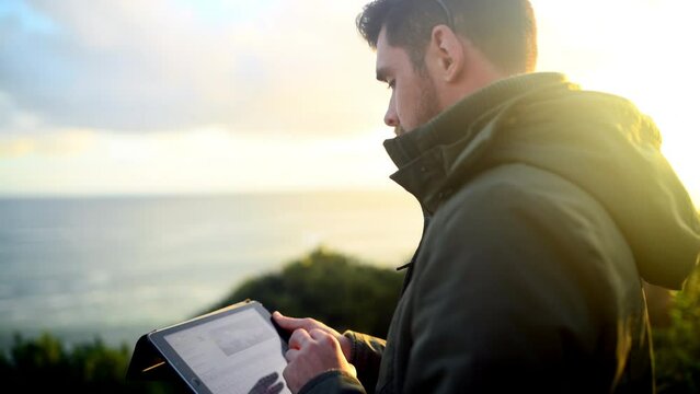 Outdoor, ocean and man with a tablet, typing and lens flare with connection, social media and website information. Person, network or guy with technology, notification and photograph with digital app