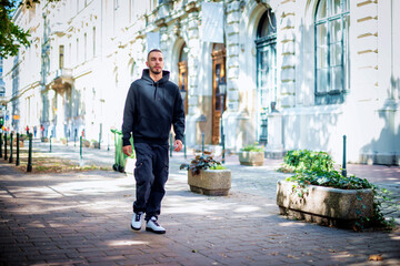 Portait of a generation Z man wearing hoodie and walking on the city street