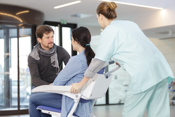 Obraz premium obstetrician doctor pushing pregnant woman in wheelchair