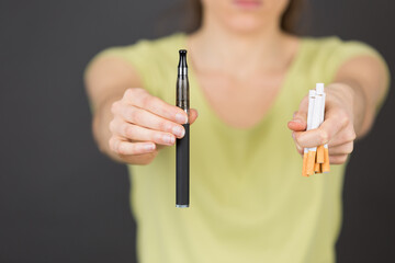 woman holding electronic cigarette and normal cigarette