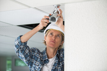 female technician installing cctv with screwdriver