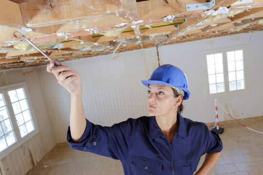 woman inspecting wooden timbers on renovation site