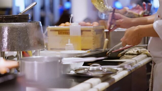 Focused chef in action a side-view capture of a dedicated chef immersed in the culinary dance of a bustling kitchen. Amidst sizzling pans and aromatic ingredients. High quality 4k footage