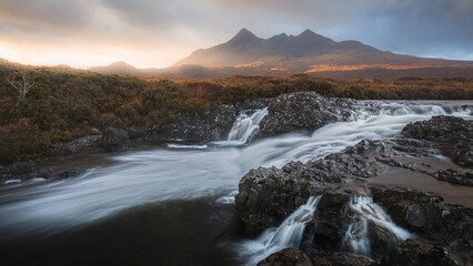 A dramatic view of the old bridge at Sligachan as the river runs beneath and the Cuillin Mountains loom large in the background.