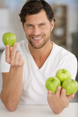 handsome young man holding green apples