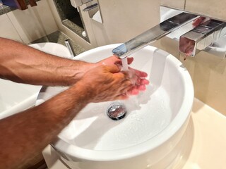 Man uses soap and washes hands with soap under tap