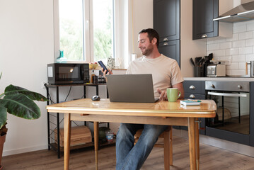 Smiling man scrolling social media during his work day at home.