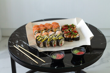 Sushi rolls in disposable paper box on table