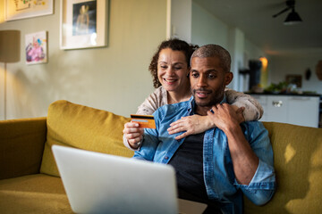 Middle aged mixed couple online shopping on a laptop from home