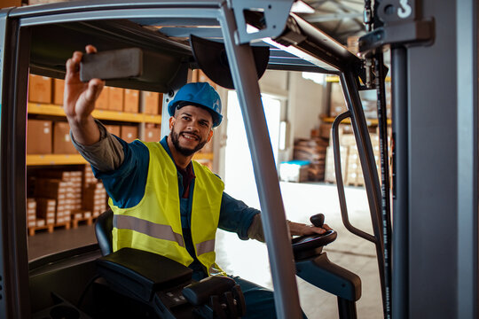 Young forklift operator taking a selfie in the warehouse