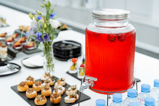 Catering in office, juice can, red lingonberry drink, sweet table, festive table setting, drink jug.