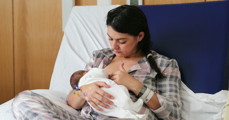 Mom breastfeeding newborn baby infant at hospital, first day of life