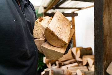 A 50 year old man has received a delivery of firewood and is putting the beech logs into the...