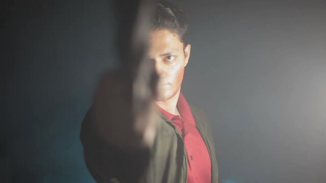 A young hitman coming from the darkness and shooting bullets, Cinematic light, and some smoke. HD footage 24 FPS.