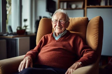 Fotobehang Elderly man in burgundy armchair watching TV in his room - middle shot portrait © Victoria