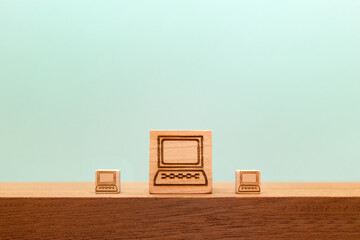 テーブルの上の小さいパソコンに挟まれた大きなパソコンマークのウッドキューブの正面 - obrazy, fototapety, plakaty
