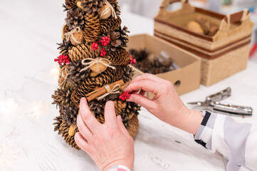 Elderly caucasian woman making cones decoration for christmas.