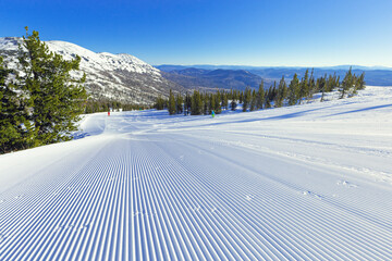 Snow velvet and blue sky on ski slope on on mount Green, Sheregesh ski resort. Prepared ski and...