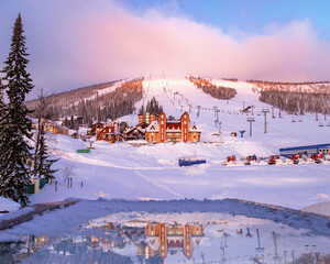 Sheregesh ski resort in Russia, picturesque sunrise, pink cloud on sky, white snow slopes and...