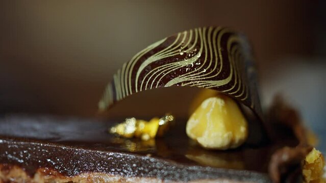 Decadent chocolate cake with golden flakes a luxurious dessert masterpiece. Moist, indulgent layers of chocolate cake are generously adorned with shimmering golden flakes. High quality 4k footage